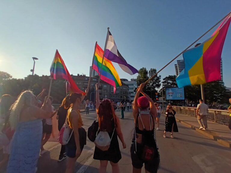 Povorka ponosa, žene nose zastave duginih boja